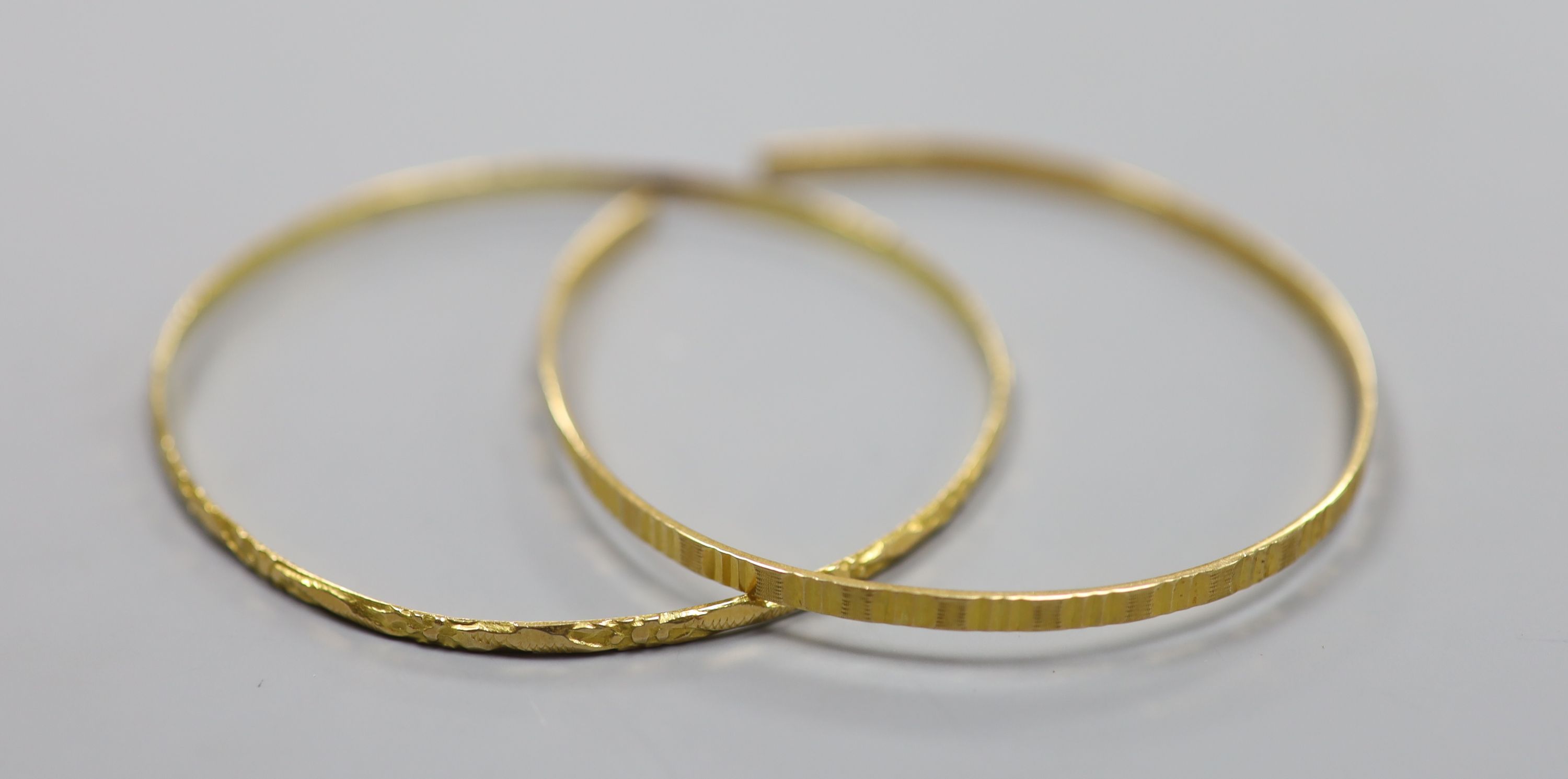 Two Middle Eastern yellow metal bangles (one cut)